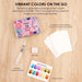 Watercolor kit with tin, paper, brush, sponge, and swatch sheet on a wooden surface.