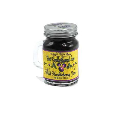 A glass jar of Wild Huckleberry Jam with a clear handle and a silver metal lid, featuring a yellow label with purple berries, on a white background.