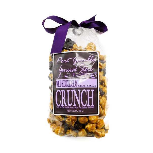 A clear plastic bag of Port Jockey's General Store Wild Hickory Berry Sea Salt Crunch, tied with a purple ribbon at the top. The bag contains a mix of golden-brown popcorn and dark berries, with a prominent black and purple label on the front.