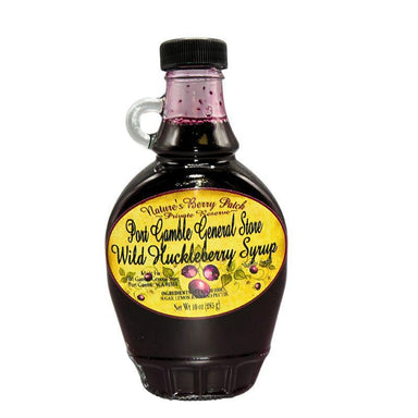A bottle of Pon Gamble General Store Wild Huckleberry Syrup on a plain white background. The syrup is a very dark purple-black color, visible through the clear glass bottle and neck.