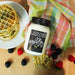 Jar of 'Wildberry Waffles' creamer with waffles and berries on a wooden surface