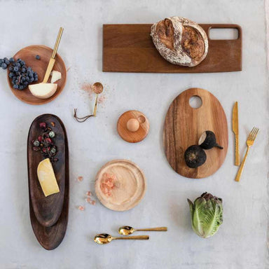 Wooden cutting boards with bread, cheese, and vegetables on a light surface