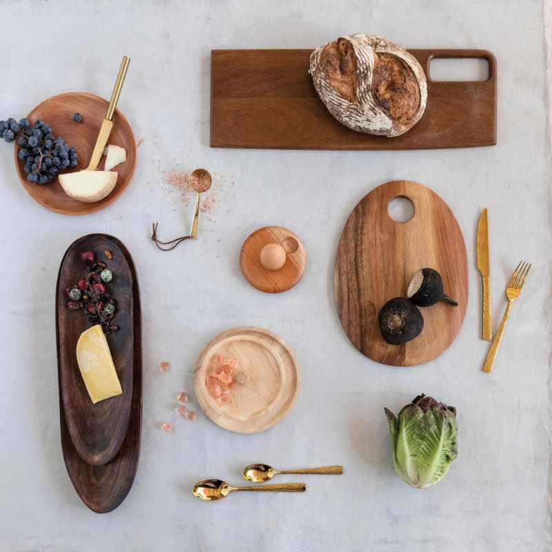 Wooden cutting boards with bread, cheese, and vegetables on a light surface