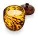 Tortoiseshell-patterned candle holder with a lit candle on a white background