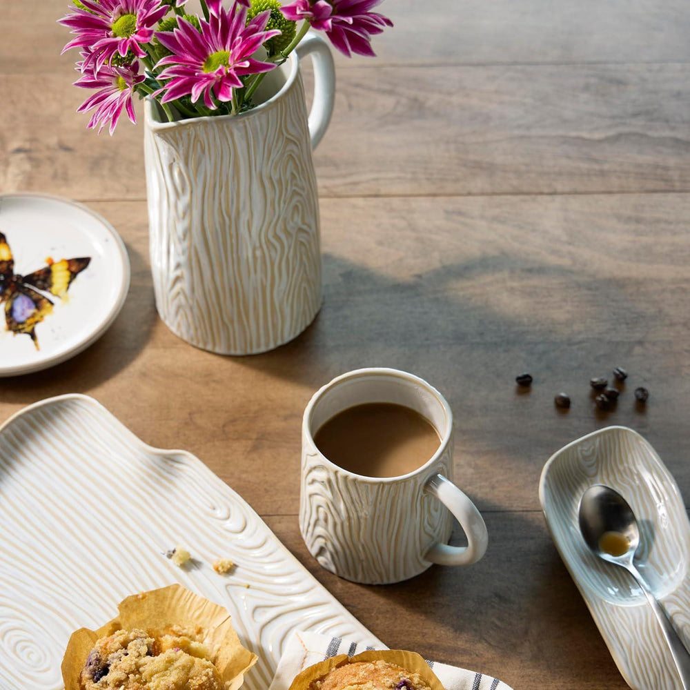 Cup of coffee with a muffin, flowers, and a butterfly on a wooden table.
