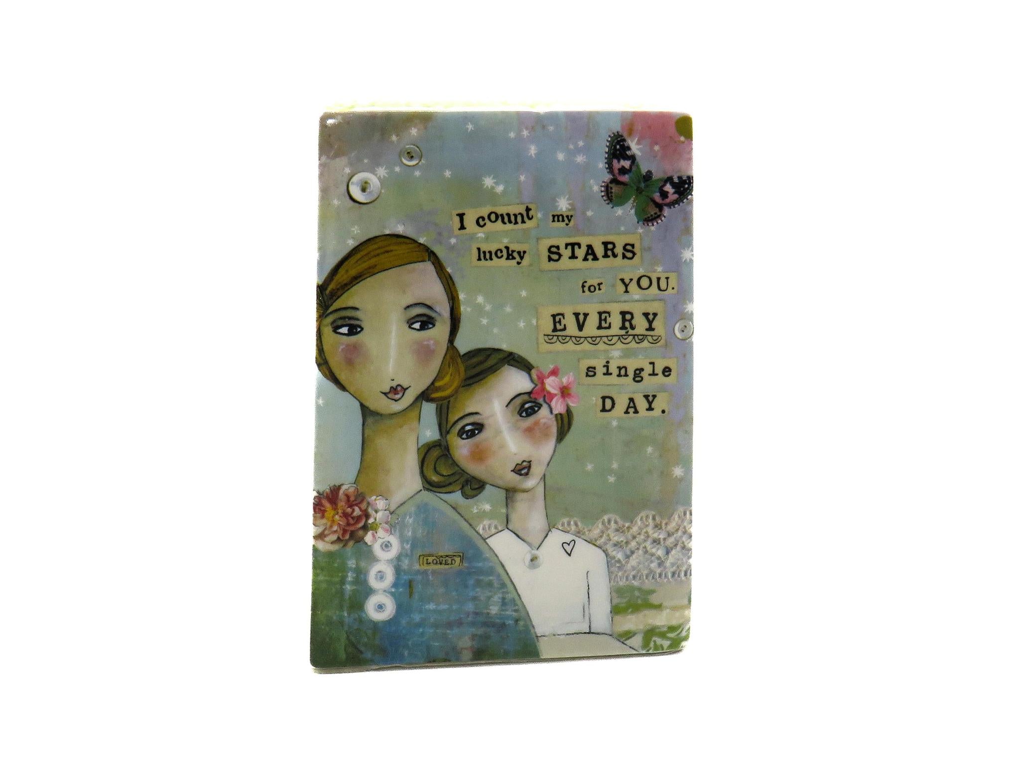  colorful creative plate features two women standing close to each other with a butterfly in view and reads the sentiment, "I count my stars for you every single day". 