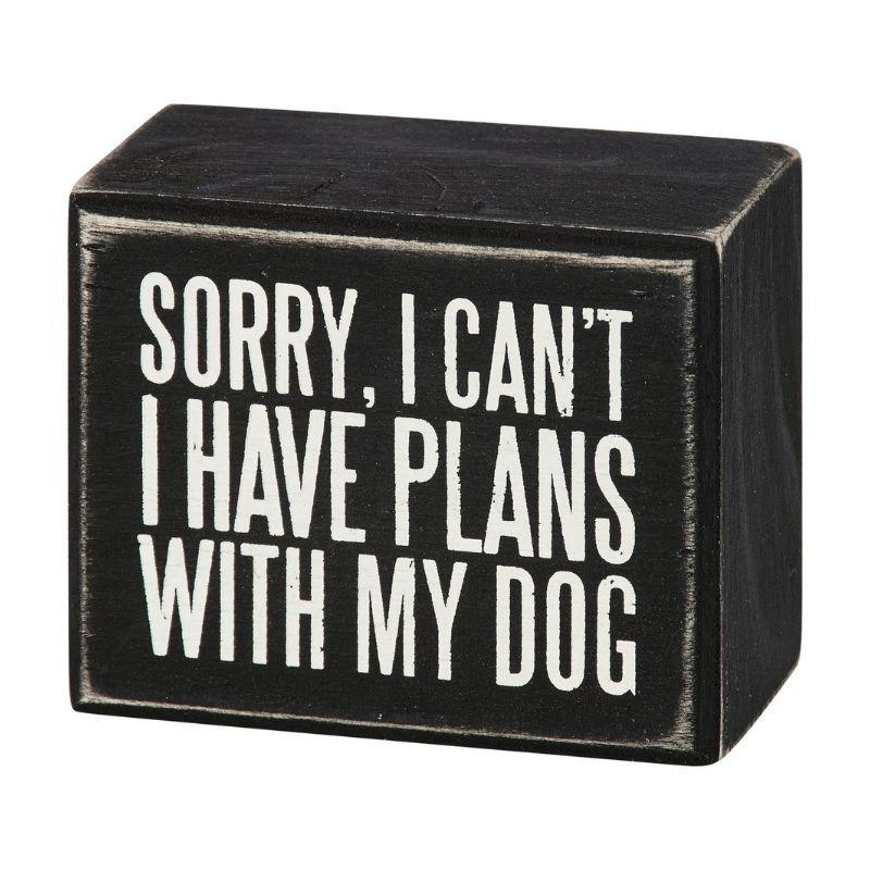 Black wooden block with white text 'Sorry, I can't. I have plans with my dog' on a white background