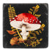 Decorative coaster with red and white mushroom design on a black background