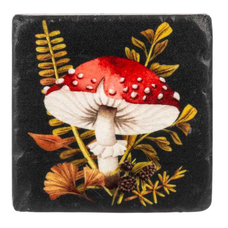 Decorative coaster with red and white mushroom design on a black background