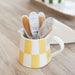 Yellow and white checkered mug with clover brand sewing notions on a wooden surface