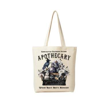 An off-white canvas tote bag with a gothic apothecary illustration, hanging on a gray wall next to a blue denim jacket. The bag features the text 'Handcrafted Feathered Potions', 'APOTHECARY', and 'WHERE MAGIC MEETS MIDNIGHT' with an illustration of a raven, glass bottles, and flowers.