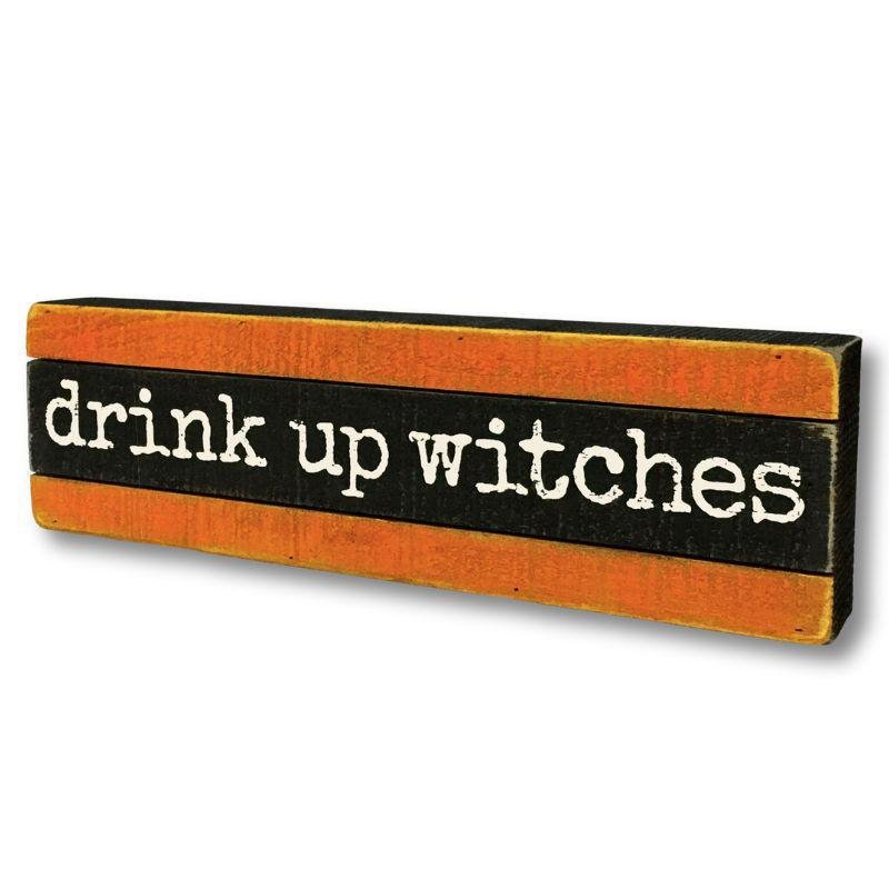 Wooden sign with 'drink up witches' text on an orange and black background