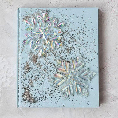 Decorative notebook with snowflake designs and glitter on a light blue background