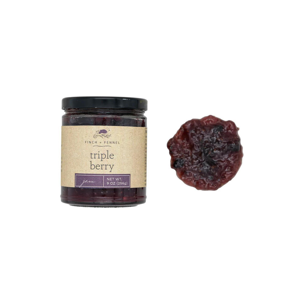 Jar of triple berry preserve with a single berry on a white background