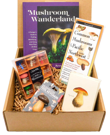 box filled with "Mushroom Wonderland" book, a guide of common mushrooms from the Pacific Northwest, a mini mushroom collection, boxed blank notes with mushroom drawings, and a mushroom tool keychain